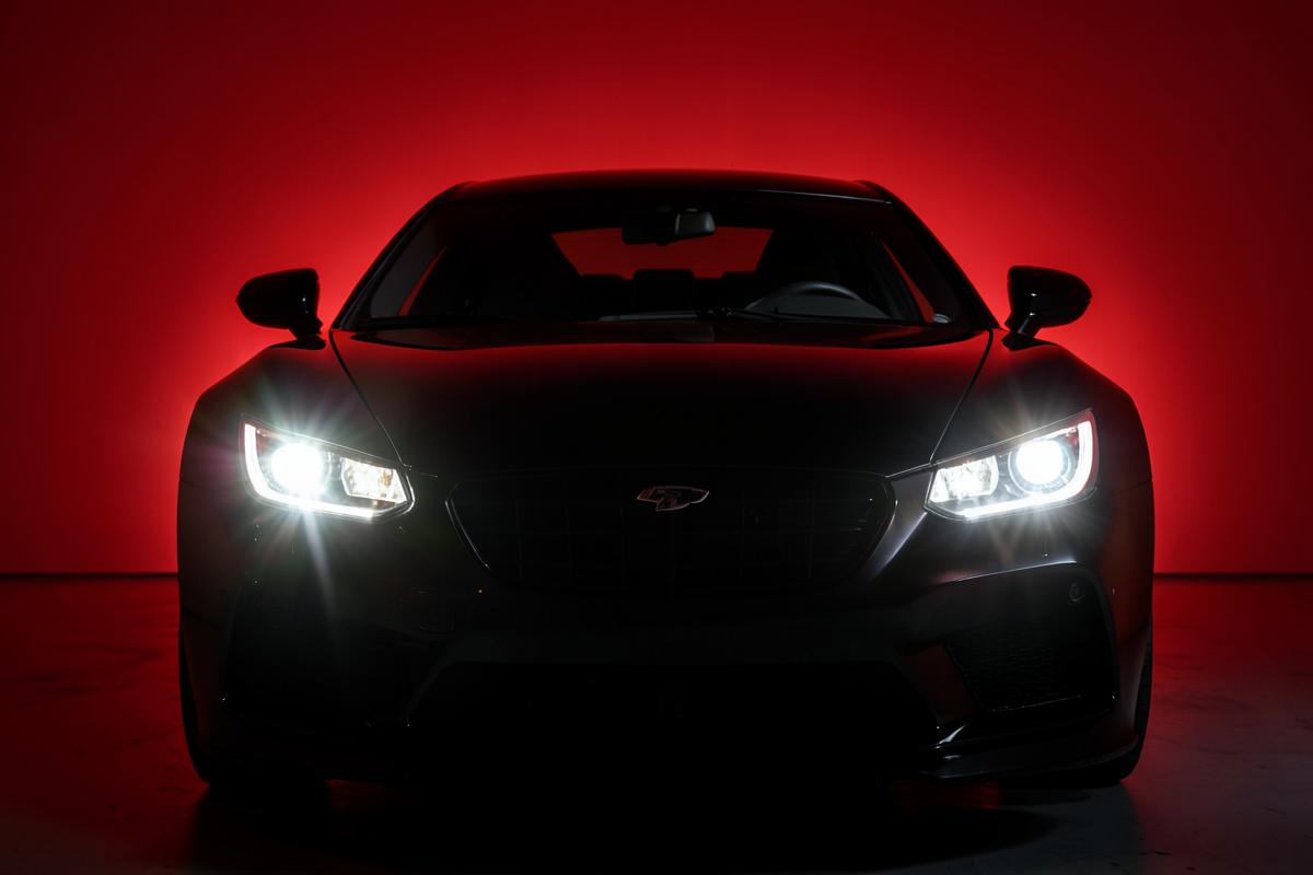 Carro esportivo preto com faróis acesos